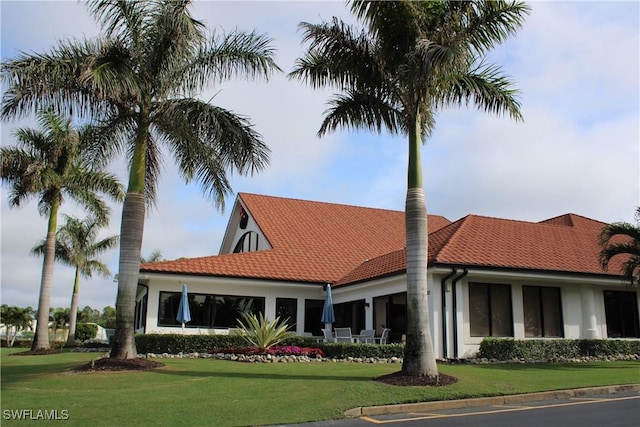 exterior space featuring a front yard, a tile roof, and stucco siding