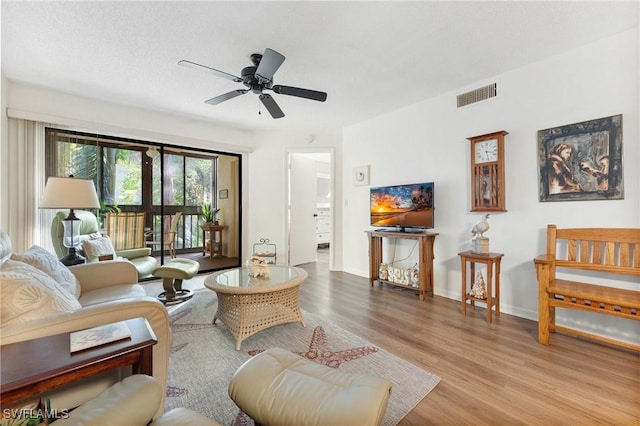 living room featuring ceiling fan, light hardwood / wood-style floors, and a textured ceiling