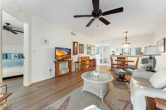 living room featuring hardwood / wood-style floors, ceiling fan, and a textured ceiling