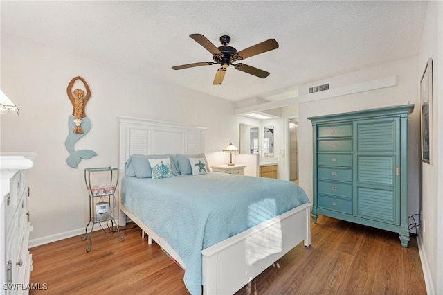 bedroom featuring a textured ceiling, ensuite bath, ceiling fan, and dark wood-type flooring