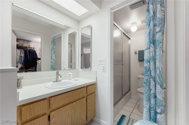 bathroom with tile patterned flooring, vanity, walk in shower, and a skylight