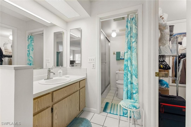 bathroom featuring tile patterned flooring, vanity, toilet, and walk in shower