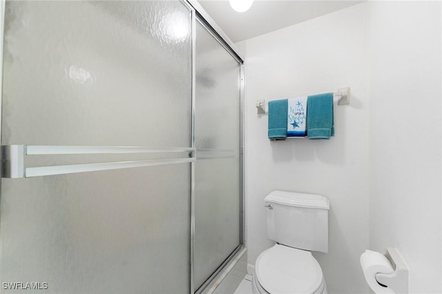 bathroom with tile patterned floors, toilet, and a shower with shower door