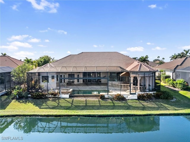 back of house featuring a lawn, glass enclosure, a fenced in pool, a water view, and a patio area