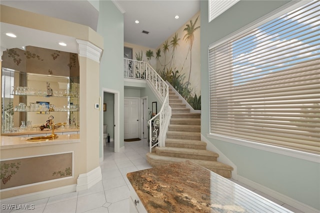 tiled foyer entrance with bar area and a towering ceiling