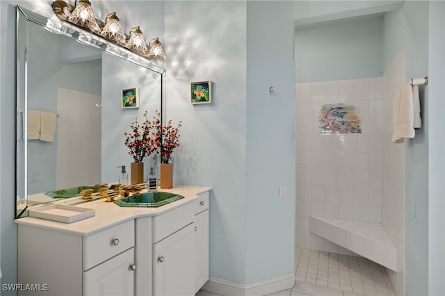 bathroom featuring tile patterned floors, vanity, and a tile shower