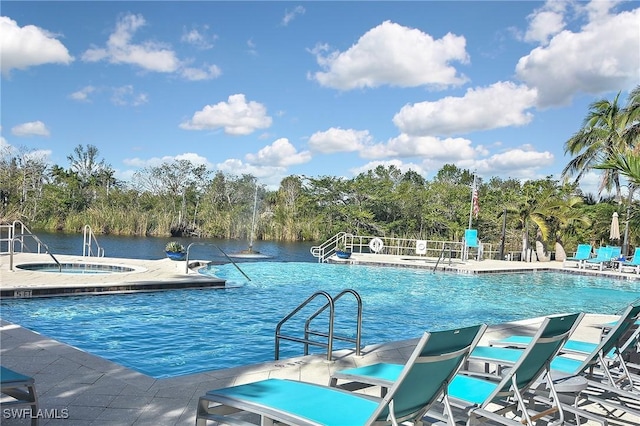 view of pool featuring a patio area, a water view, and a hot tub