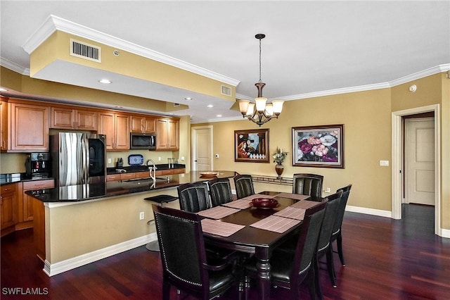 dining area with dark hardwood / wood-style flooring, sink, crown molding, and a chandelier