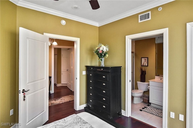 bedroom featuring hardwood / wood-style floors, ceiling fan with notable chandelier, crown molding, and connected bathroom