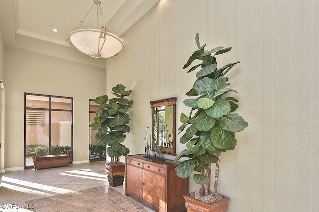 interior space with light tile patterned floors, ornamental molding, and a towering ceiling