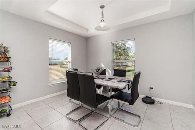 dining space with a healthy amount of sunlight, light tile patterned floors, and a tray ceiling