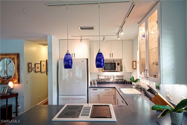 kitchen with sink, cooktop, white refrigerator, pendant lighting, and white cabinets