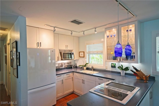 kitchen with sink, white refrigerator, decorative light fixtures, stovetop, and white cabinets