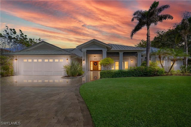 view of front of house featuring decorative driveway, a front yard, a standing seam roof, metal roof, and a garage