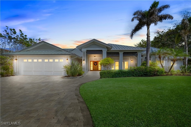 view of front of home featuring a garage, metal roof, a standing seam roof, decorative driveway, and a front lawn