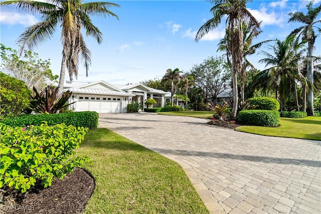 view of front of house with a garage, a front yard, and decorative driveway