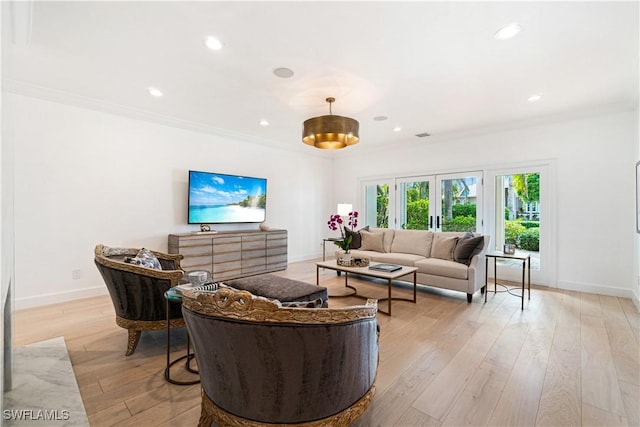 living room with light hardwood / wood-style floors, ornamental molding, and french doors