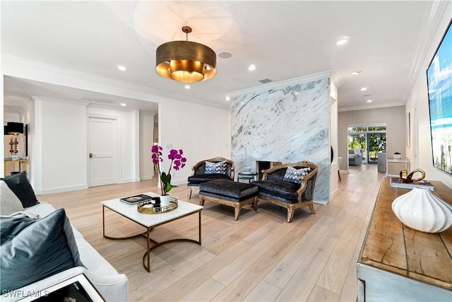 living room with a fireplace, light hardwood / wood-style floors, and crown molding