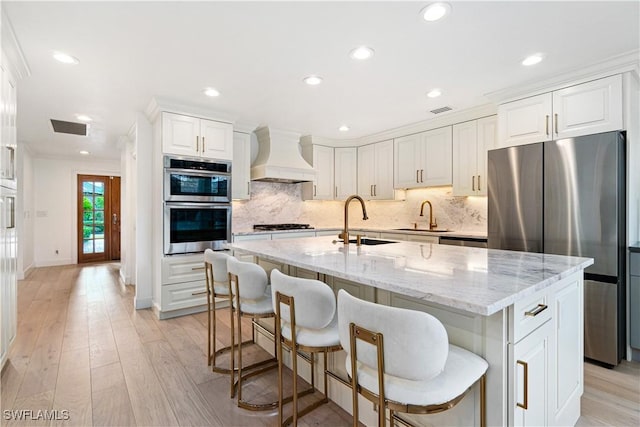 kitchen featuring sink, white cabinets, stainless steel appliances, and custom range hood