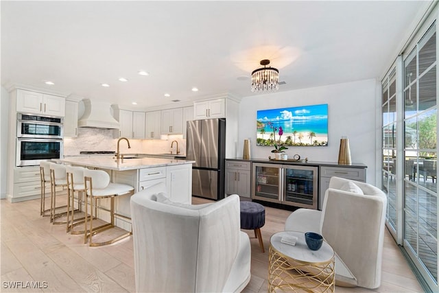 kitchen featuring premium range hood, white cabinetry, stainless steel appliances, and light wood-type flooring