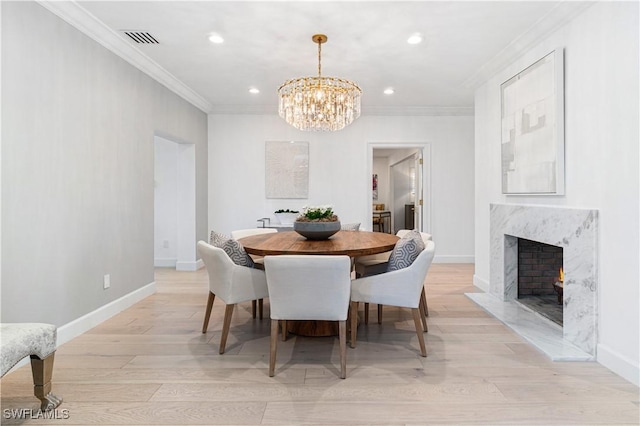 dining room with a fireplace, light wood-type flooring, a chandelier, and ornamental molding