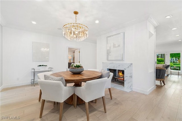 dining room featuring a high end fireplace, light hardwood / wood-style floors, and ornamental molding