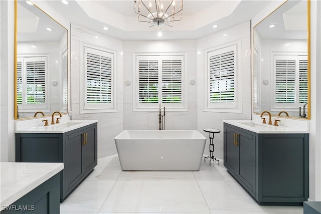 bathroom featuring a bathtub, a raised ceiling, tile walls, and a chandelier