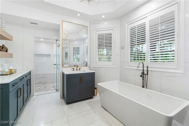 bathroom with separate shower and tub, vanity, tile walls, and an inviting chandelier