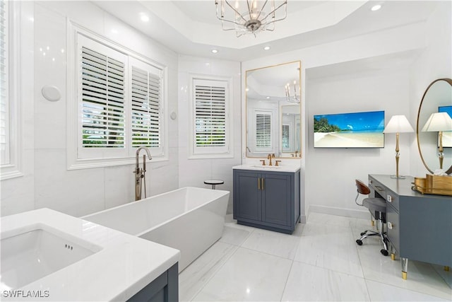 bathroom with a tub, tile patterned floors, a chandelier, a tray ceiling, and vanity