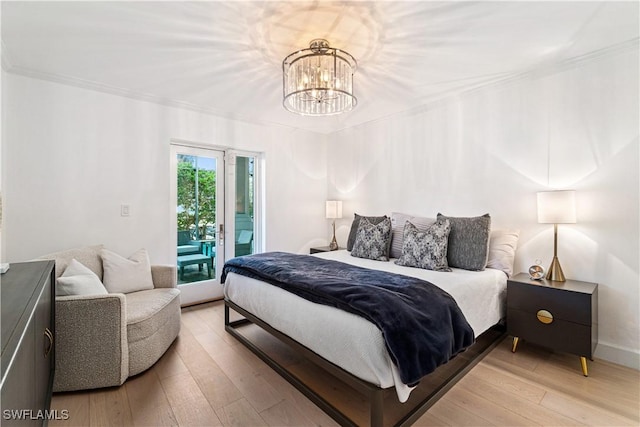 bedroom with access to exterior, light hardwood / wood-style flooring, and an inviting chandelier