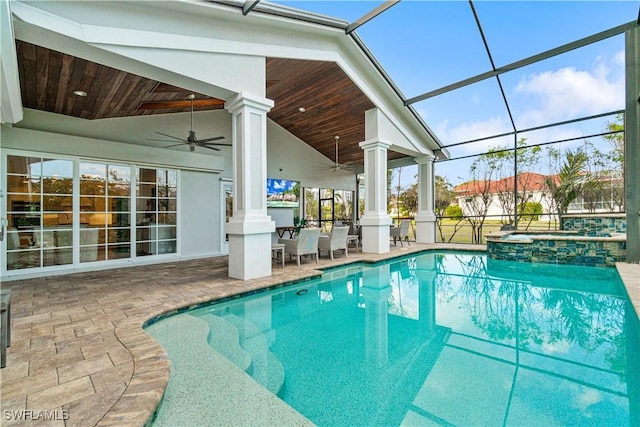 view of pool with glass enclosure, ceiling fan, a patio, and an in ground hot tub