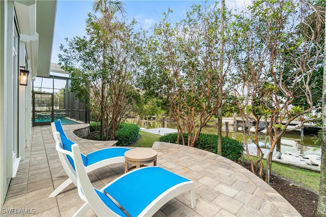 view of patio with a lanai and a water view