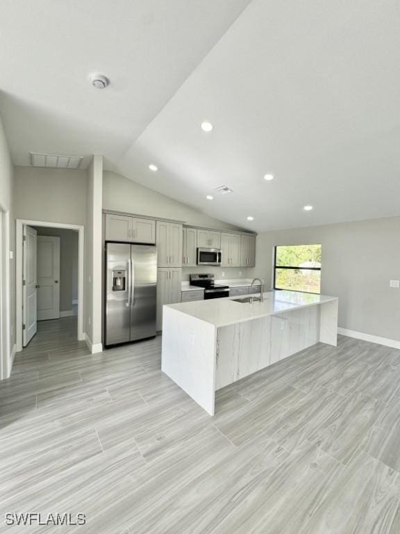 kitchen featuring gray cabinetry, a kitchen island with sink, sink, and appliances with stainless steel finishes