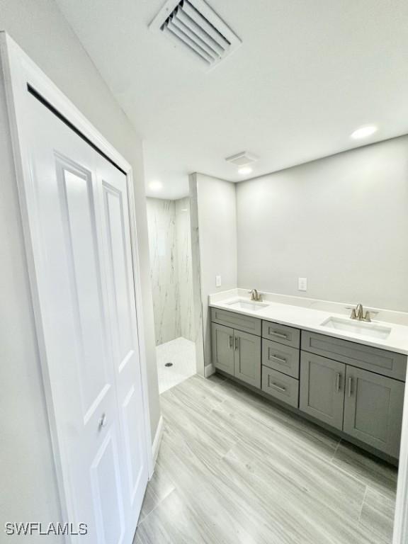 bathroom with hardwood / wood-style floors, vanity, and tiled shower