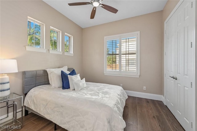 bedroom with a closet, baseboards, dark wood-style floors, and a ceiling fan