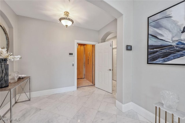 interior space with baseboards, arched walkways, and marble finish floor