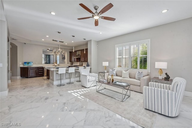 living room featuring recessed lighting, marble finish floor, and baseboards