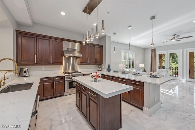 kitchen featuring a peninsula, stainless steel stove, marble finish floor, wall chimney exhaust hood, and a sink