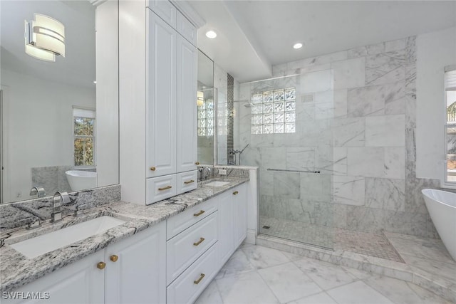 bathroom with a shower stall, double vanity, a soaking tub, marble finish floor, and a sink