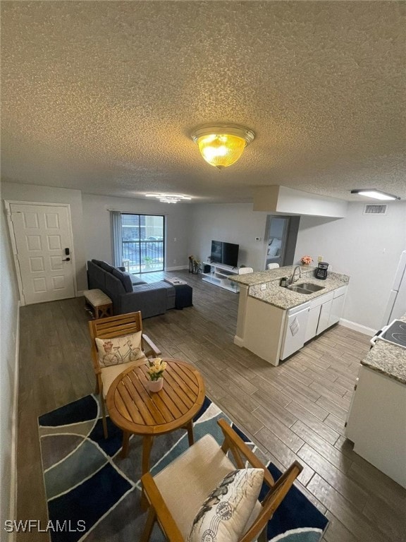 kitchen with a textured ceiling, white cabinetry, sink, and hardwood / wood-style floors