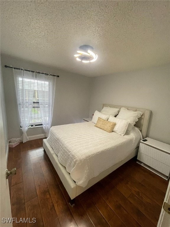 bedroom featuring a textured ceiling and dark wood-type flooring