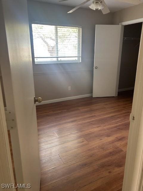 unfurnished bedroom featuring ceiling fan, a closet, and dark wood-type flooring