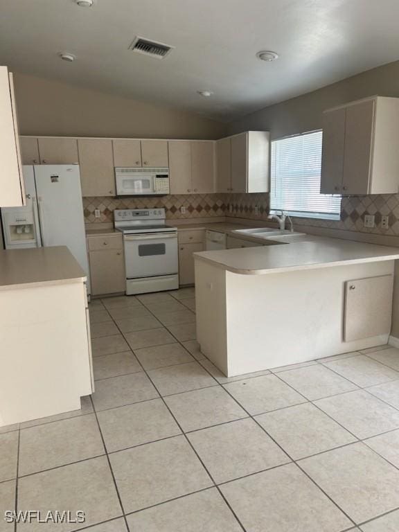 kitchen with white appliances, sink, vaulted ceiling, cream cabinetry, and kitchen peninsula