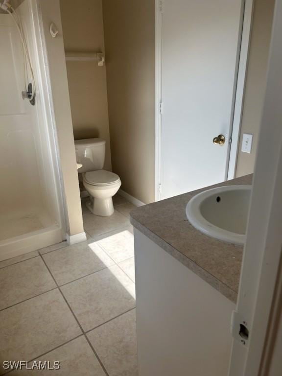 bathroom with tile patterned flooring, vanity, toilet, and walk in shower