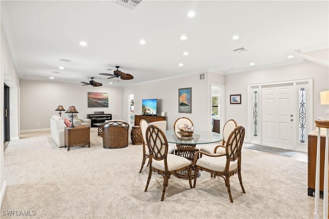 carpeted dining room featuring ceiling fan and ornamental molding