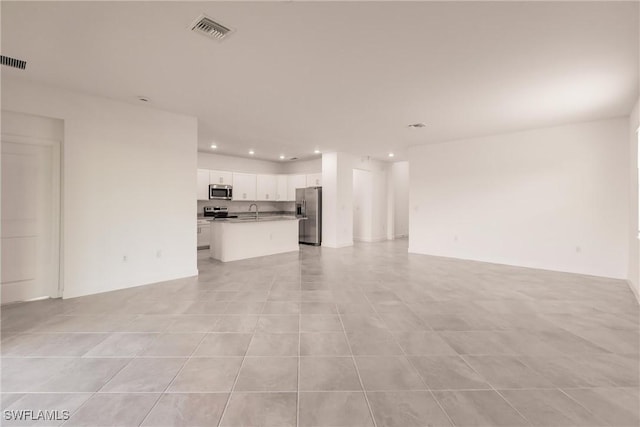 unfurnished living room featuring light tile patterned floors and sink