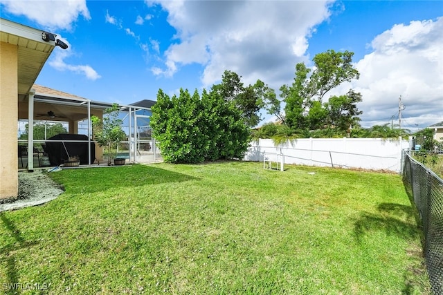 view of yard featuring ceiling fan and a lanai