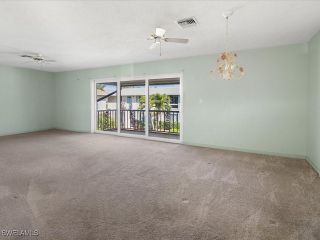 carpeted empty room featuring ceiling fan with notable chandelier