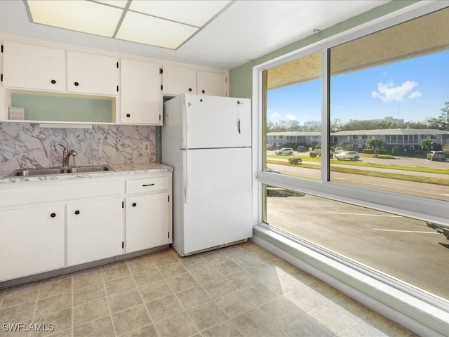 kitchen with decorative backsplash, white refrigerator, white cabinetry, and sink