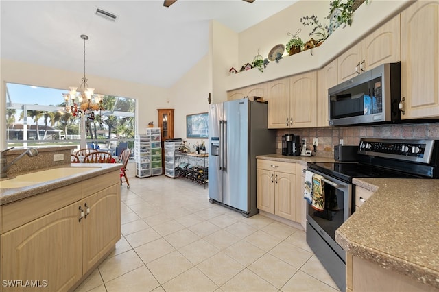 kitchen featuring sink, stainless steel appliances, an inviting chandelier, pendant lighting, and light tile patterned floors